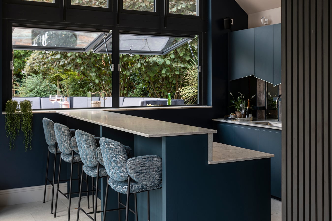 Close-up of angled navy blue kitchen cabinetry with reflective wood panelling